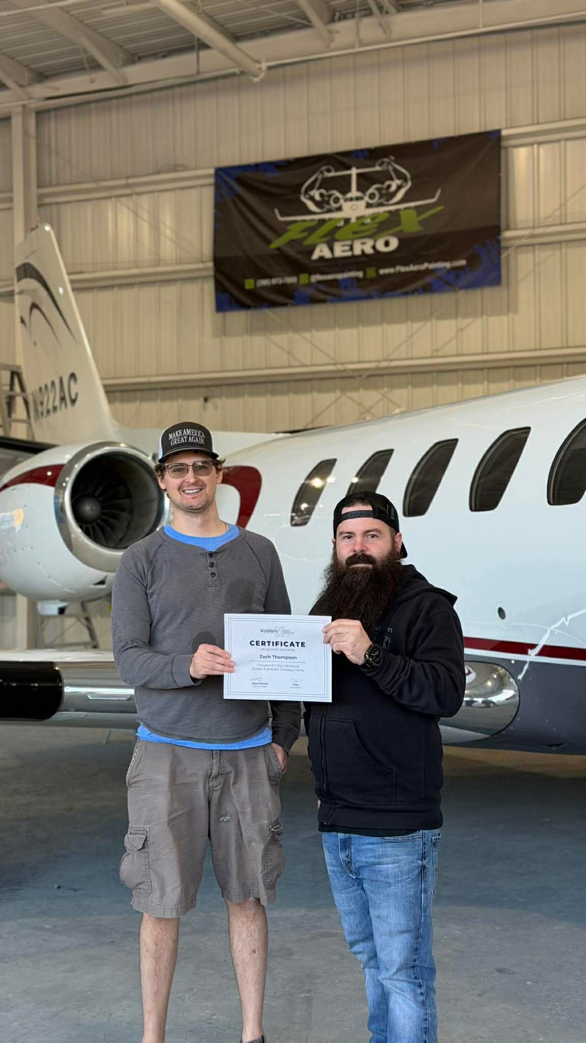 Zachary Thompson with his System X advanced aviation training certificate beside a business jet